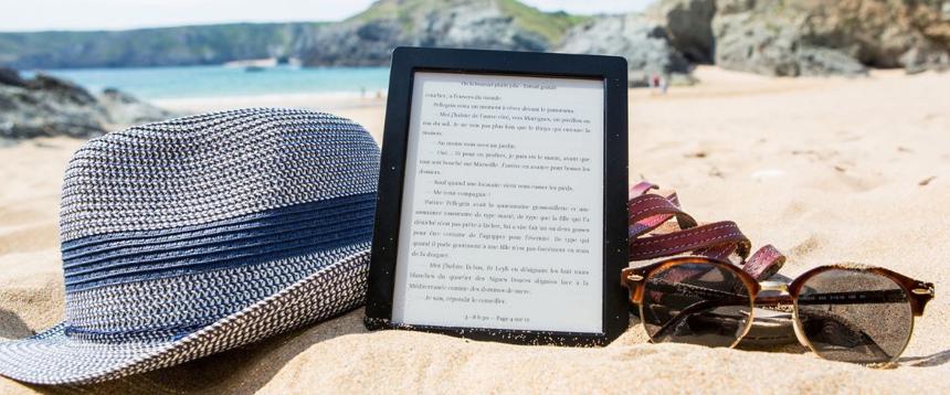 Photograph of eReader tablet on sandy beach with hat and sunglasses