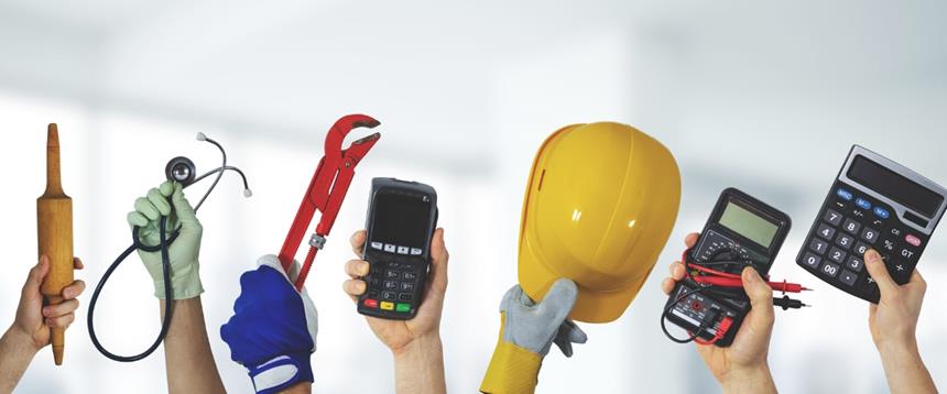 Hands holding up a rolling pin, stethoscope, wrench, card reader, construction hat, electricity monitor and calculator
