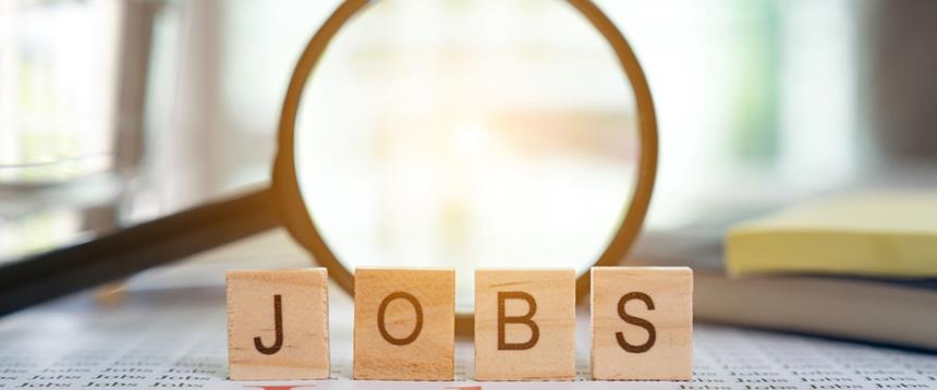 Scrabble tiles spelling the word "Jobs" placed in front of a magnifying glass