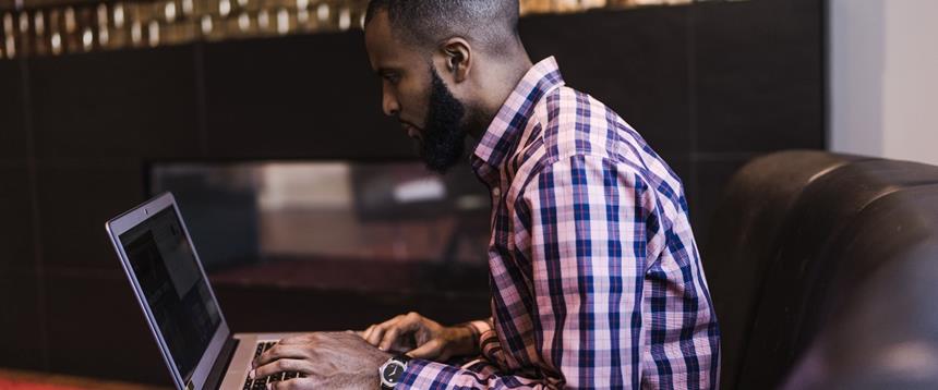 Man sitting on couch using laptop