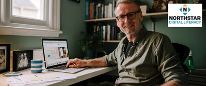 A man sitting at a desk in his home with his laptop open and the Northstar Digital Literacy logo in the top right corner